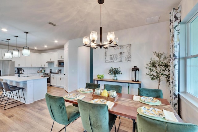 dining space featuring light hardwood / wood-style floors, sink, and a chandelier