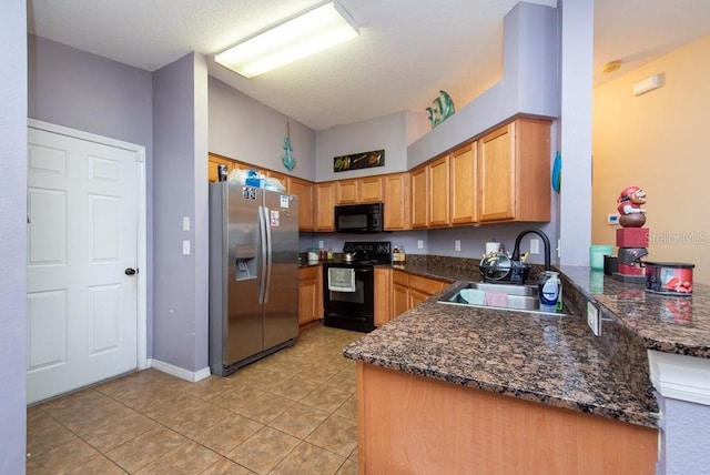 kitchen featuring sink, kitchen peninsula, dark stone countertops, light tile patterned flooring, and black appliances