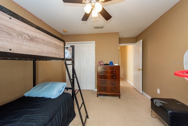 bedroom with ceiling fan, light colored carpet, and a closet