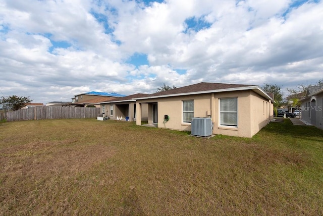 rear view of house with a lawn and central air condition unit