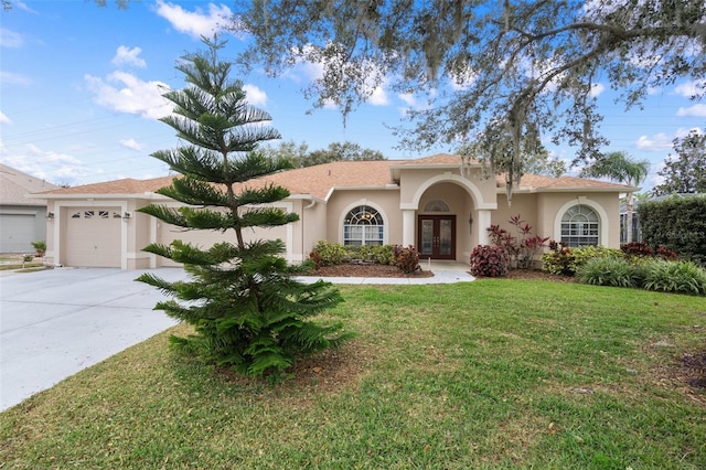 mediterranean / spanish house featuring french doors, a garage, and a front lawn