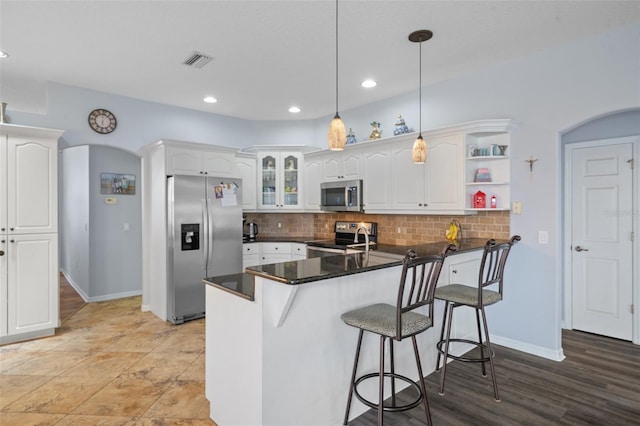 kitchen with white cabinets, kitchen peninsula, stainless steel appliances, and hanging light fixtures