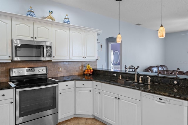 kitchen with pendant lighting, sink, light tile patterned floors, appliances with stainless steel finishes, and white cabinetry