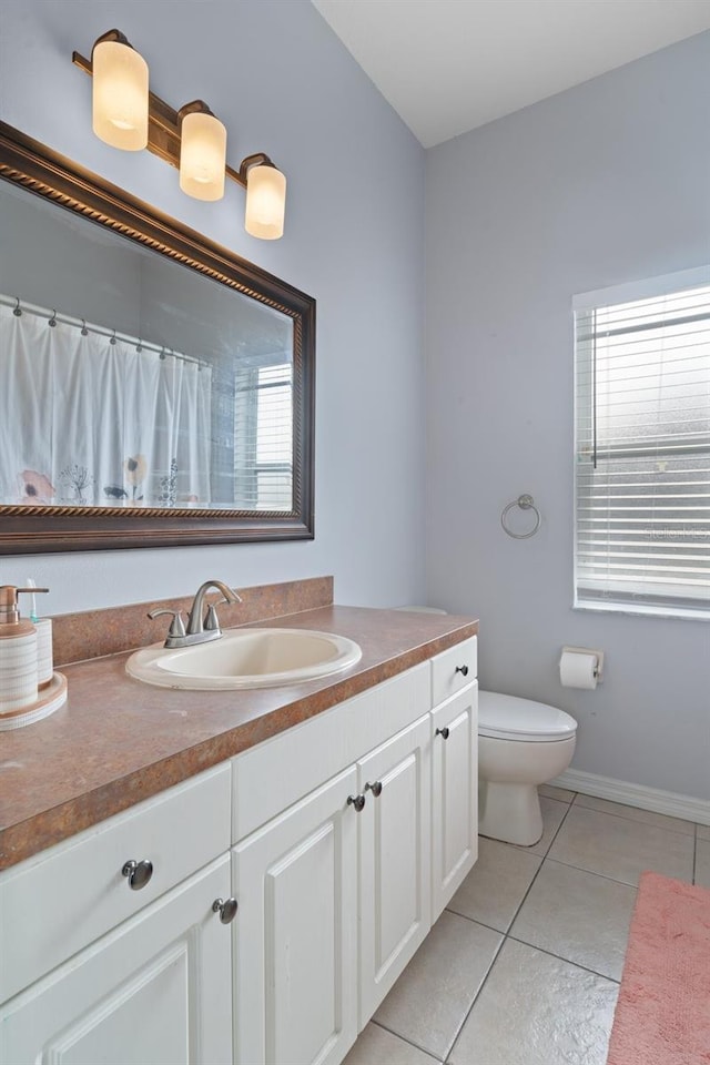 bathroom with toilet, vanity, and tile patterned floors