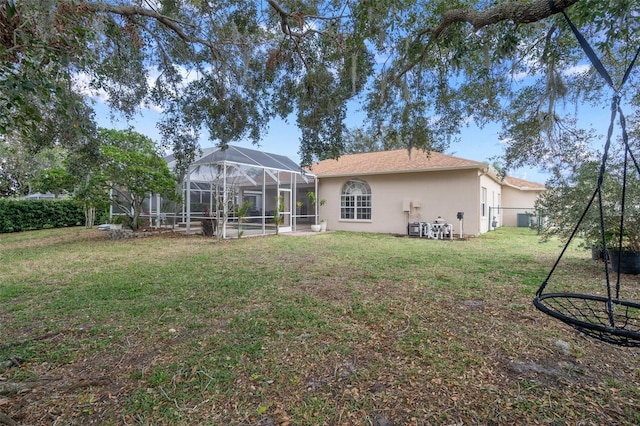 back of property with glass enclosure and a yard