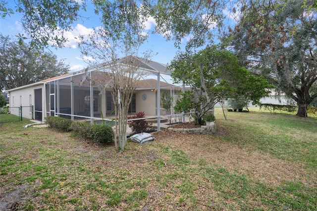 back of property featuring glass enclosure and a yard