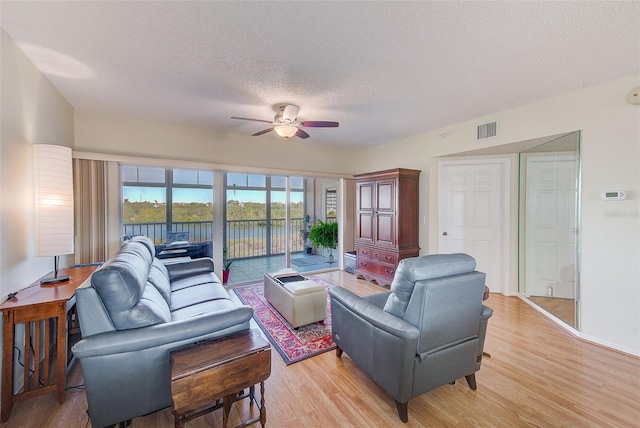 living room featuring a textured ceiling, ceiling fan, and light wood-type flooring