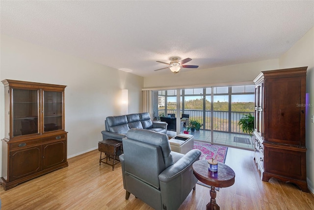 living room with light wood-type flooring, ceiling fan, and a textured ceiling