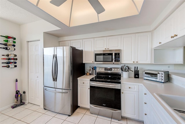 kitchen with light tile patterned floors, appliances with stainless steel finishes, and white cabinets