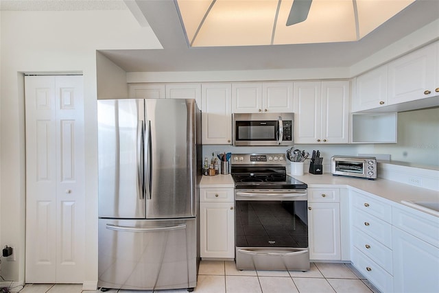 kitchen with light tile patterned flooring, ceiling fan, appliances with stainless steel finishes, and white cabinets