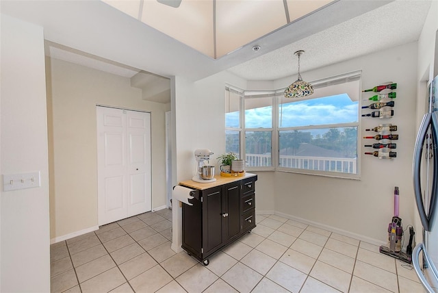 kitchen with hanging light fixtures, light tile patterned floors, refrigerator, and a textured ceiling