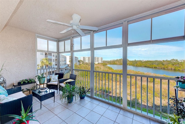 sunroom with ceiling fan and a water view