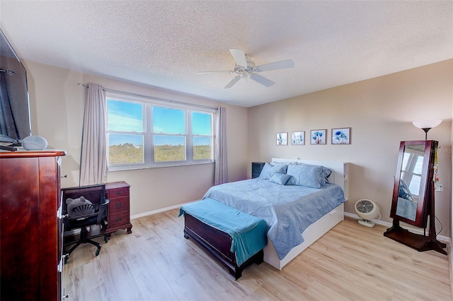 bedroom with ceiling fan, light wood-type flooring, and a textured ceiling