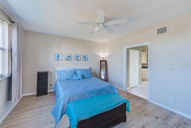 bedroom with light wood-type flooring, ceiling fan, and a textured ceiling