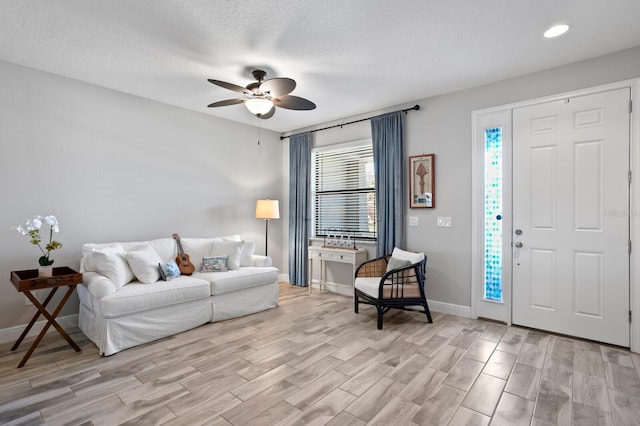 living room featuring ceiling fan, a textured ceiling, and light wood-type flooring