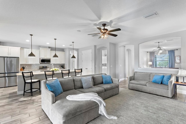 living room featuring sink, ceiling fan, and light wood-type flooring