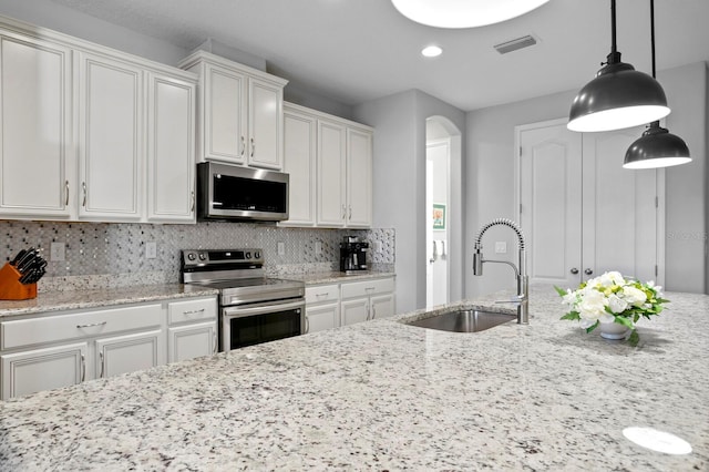 kitchen with pendant lighting, appliances with stainless steel finishes, sink, and white cabinets