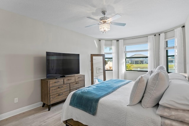 bedroom with ceiling fan, light hardwood / wood-style floors, and a textured ceiling