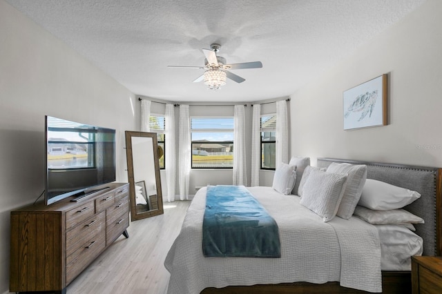 bedroom featuring ceiling fan, a textured ceiling, and light hardwood / wood-style floors