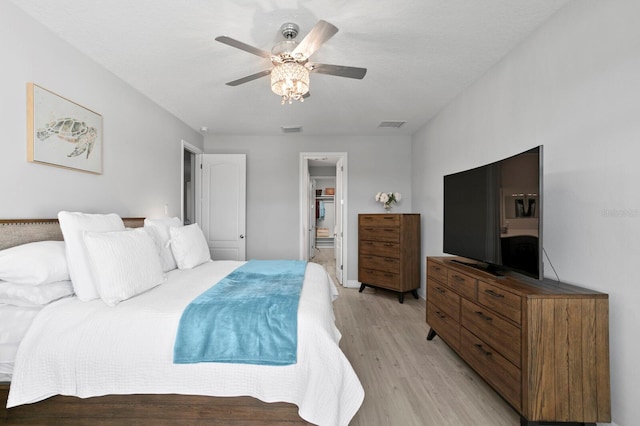 bedroom with ensuite bathroom, a textured ceiling, ceiling fan, and light wood-type flooring