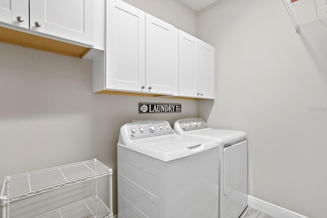 clothes washing area with cabinets and washing machine and dryer