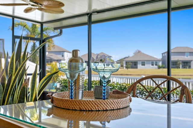 sunroom / solarium featuring ceiling fan and a water view