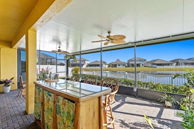 sunroom / solarium with a water view and ceiling fan