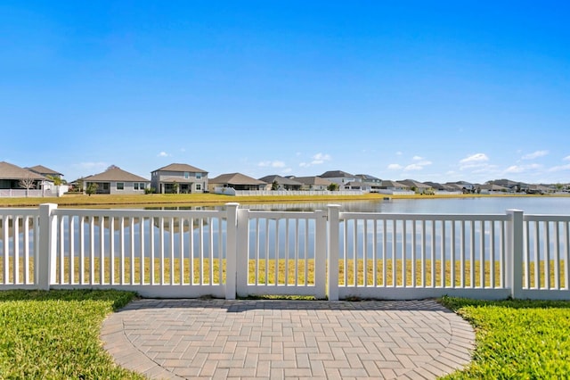 view of gate featuring a water view and a patio area