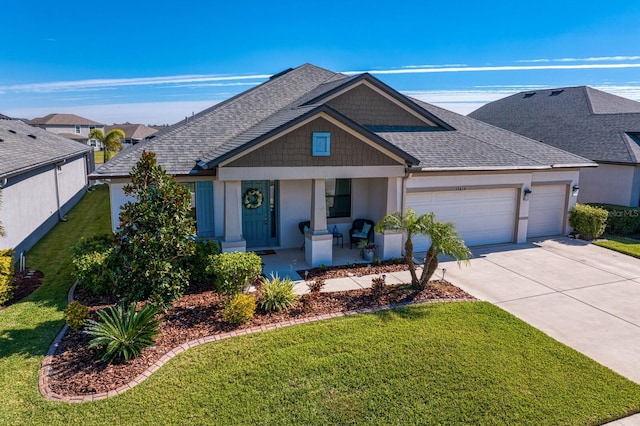 view of front of home with a garage, a front yard, and covered porch