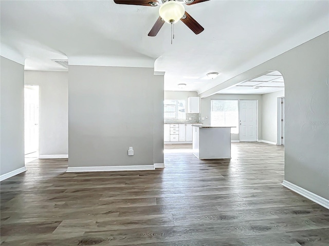 unfurnished living room with ceiling fan and dark wood-type flooring