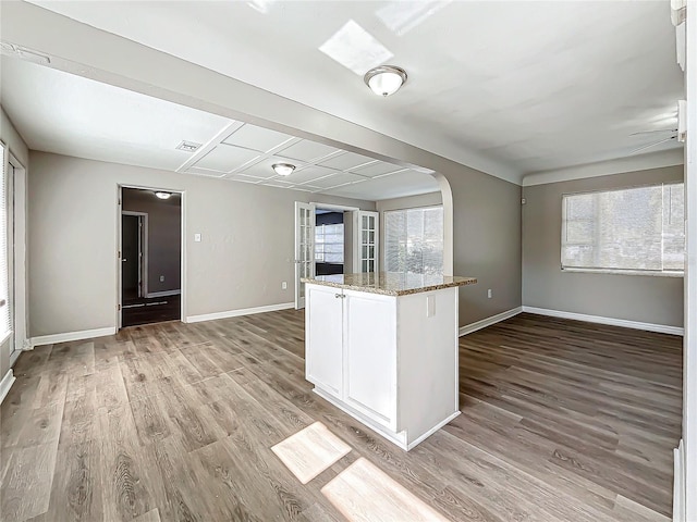 kitchen featuring ceiling fan, light stone counters, white cabinetry, and light hardwood / wood-style flooring