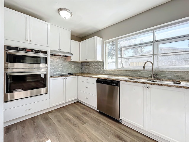 kitchen featuring tasteful backsplash, stainless steel appliances, sink, stone countertops, and white cabinetry