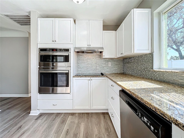 kitchen featuring light stone countertops, appliances with stainless steel finishes, light hardwood / wood-style floors, white cabinetry, and plenty of natural light