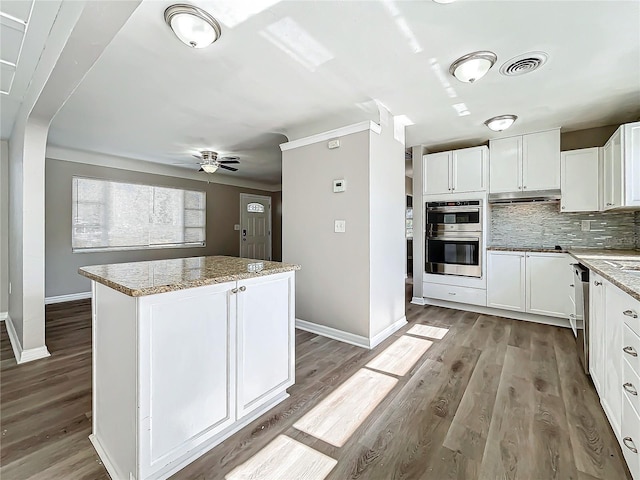 kitchen featuring stainless steel appliances, a kitchen island, tasteful backsplash, light hardwood / wood-style floors, and white cabinets