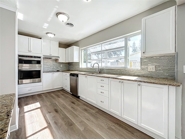 kitchen featuring sink, light hardwood / wood-style floors, stone countertops, white cabinets, and appliances with stainless steel finishes