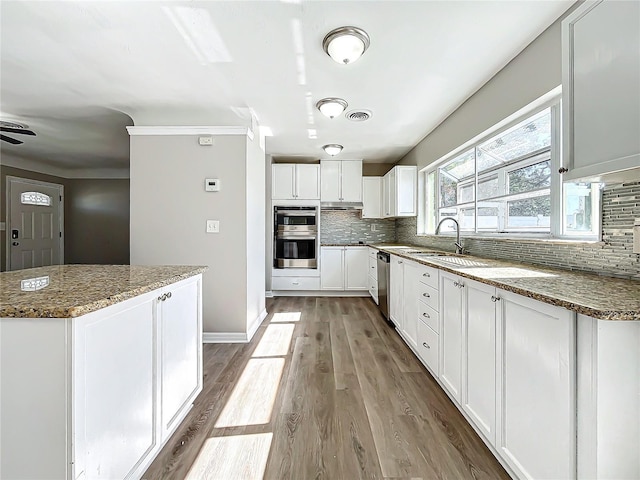 kitchen featuring decorative backsplash, stainless steel appliances, stone countertops, white cabinets, and light hardwood / wood-style floors