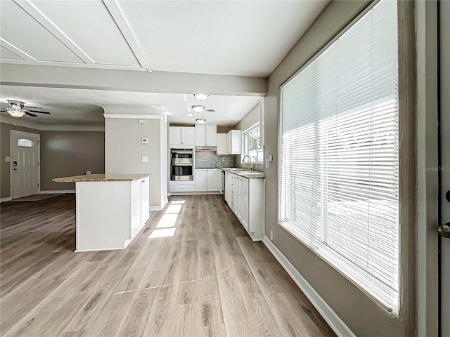 kitchen featuring tasteful backsplash, a wealth of natural light, sink, and white cabinets