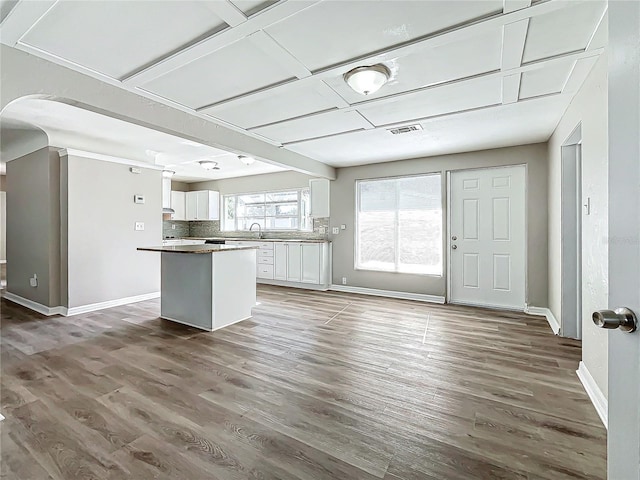 kitchen featuring white cabinetry, a center island, sink, tasteful backsplash, and hardwood / wood-style flooring