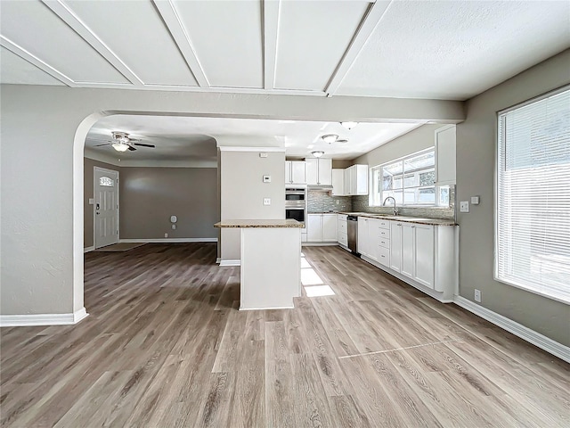 kitchen featuring white cabinetry, ceiling fan, stainless steel appliances, a kitchen island, and light wood-type flooring