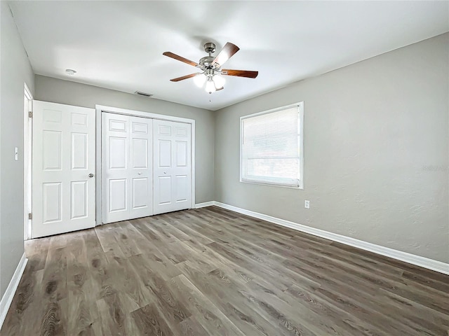 unfurnished bedroom featuring a closet, ceiling fan, and dark wood-type flooring