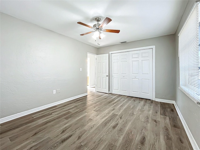 unfurnished bedroom featuring hardwood / wood-style floors, a closet, and ceiling fan