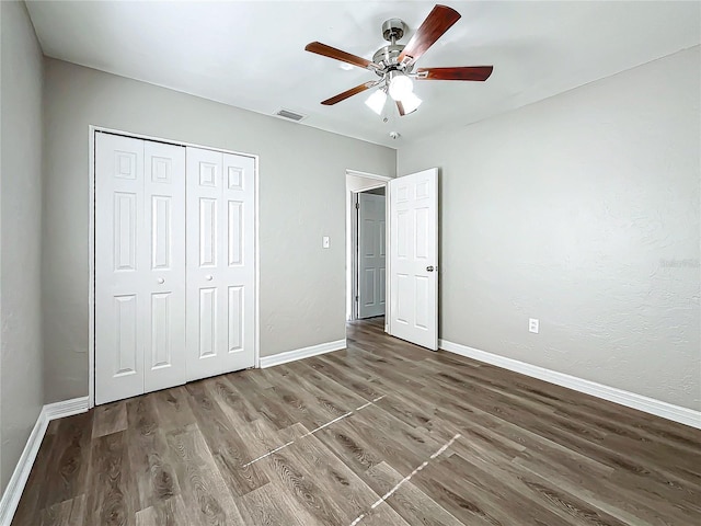 unfurnished bedroom featuring ceiling fan, dark hardwood / wood-style floors, and a closet