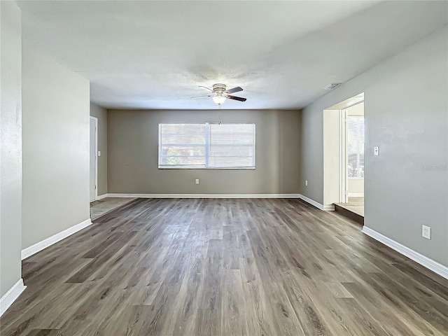 unfurnished room featuring ceiling fan, a healthy amount of sunlight, and dark hardwood / wood-style flooring