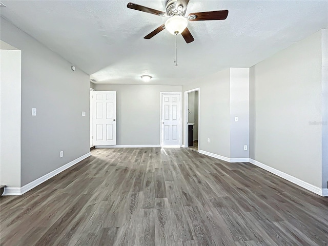 empty room featuring ceiling fan, dark wood-type flooring, and a textured ceiling