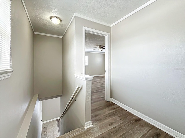 stairs featuring a textured ceiling, ceiling fan, crown molding, and hardwood / wood-style flooring