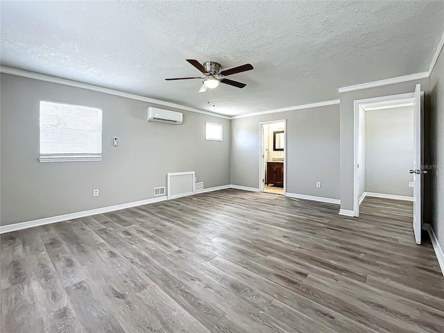 unfurnished bedroom featuring a wall unit AC, connected bathroom, ceiling fan, and hardwood / wood-style floors