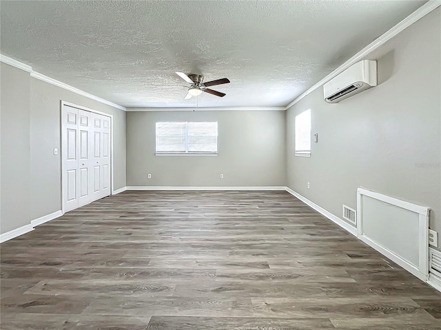 unfurnished bedroom with multiple windows, ceiling fan, dark hardwood / wood-style flooring, and a wall mounted air conditioner