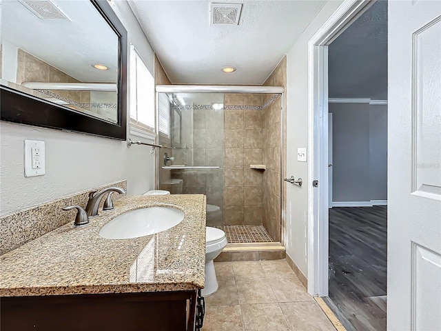 bathroom with tile patterned floors, vanity, toilet, and a shower with door