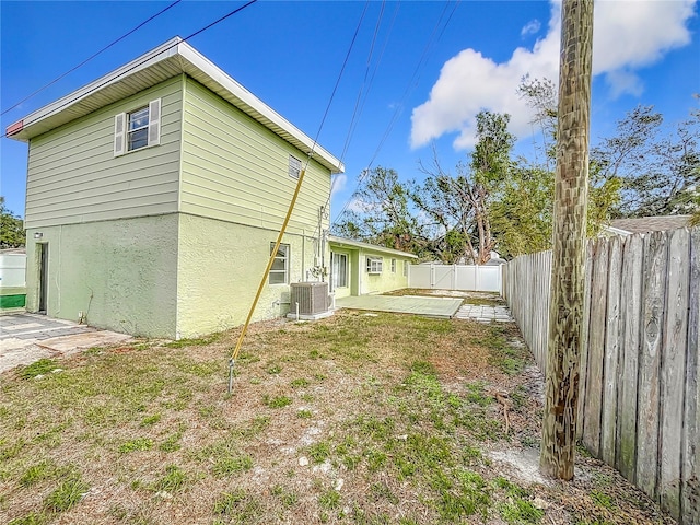 back of house featuring a yard, central AC unit, and a patio area