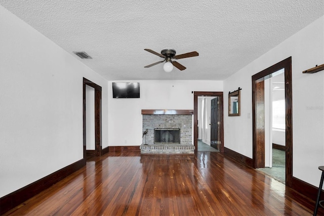 unfurnished living room with ceiling fan, a fireplace, dark hardwood / wood-style floors, and a textured ceiling